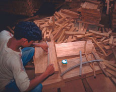 A worker marks patterns for furniture pieces onto blanks.